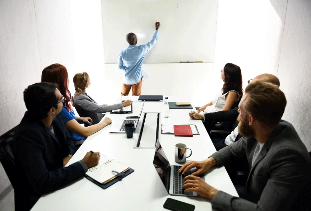 A team working through a plan together at a whiteboard